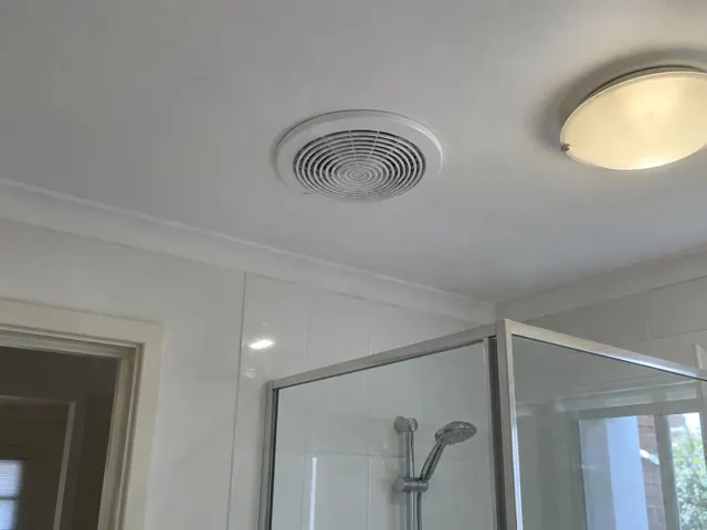 Bathroom ceiling exhaust fan above a tiled shower with a flush ceiling light in Southport
